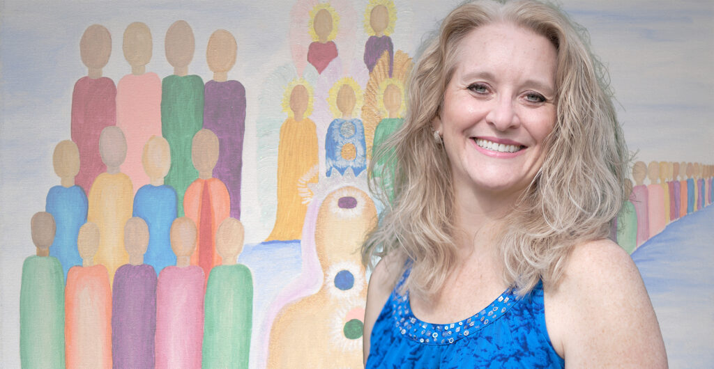 Karen Kubicko standing in front of one of her colorful paintings.